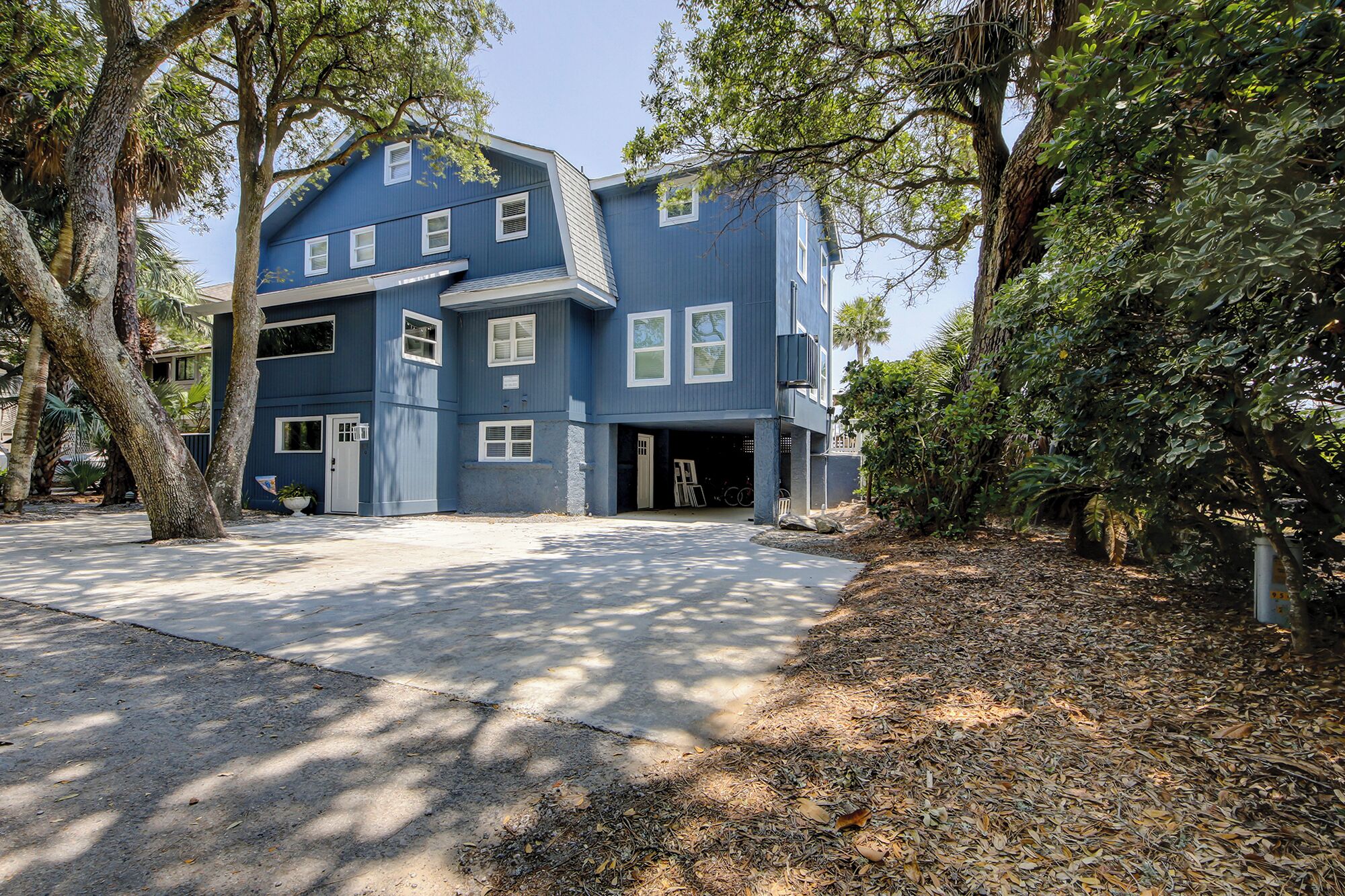 A two-story house with a garage, surrounded by trees and a driveway.