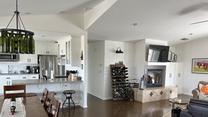 Eine moderne Küche mit weißen Schränken, Edelstahlgeräten und einem Weinregal.