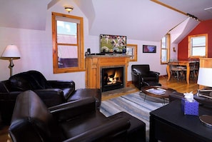 A living room with a fireplace, leather furniture, and a television.