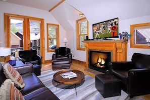 A cozy living room with leather furniture, a fireplace, and a television.