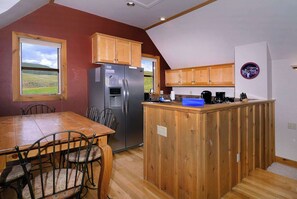 A kitchen with wooden cabinets, a refrigerator, a coffee maker, and a dining table with chairs. - Horseshoe House, Close to shuttle, Pitchfork. (Mt. Crested Butte)