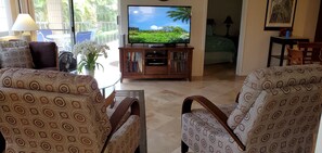 Een woonkamer met gestoffeerde meubels, een televisietoestel en uitzicht op de omgeving.