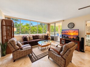 A spacious living room with a sofa, armchairs, a coffee table, and a TV.