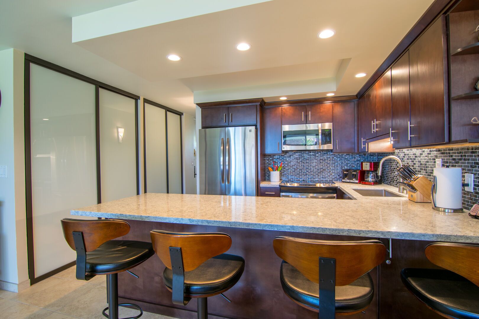 A modern kitchen with dark wood cabinets, stainless steel appliances, and a granite countertop.