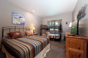A bedroom with a bunk bed, a single bed, a wooden dresser, a lamp, a television, and a poster on the wall. - Newly Furnished and remodeled condo/Heated Pool (Durango)