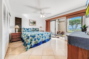 A bedroom with a bed, a nightstand, a lamp, a ceiling fan, a sliding glass door to a balcony, and a framed picture on the wall. - Wailea Ekolu #501 Panoramic Ocean View, Ground Floor, Wifi, A/C, Near Beach (Wailea)
