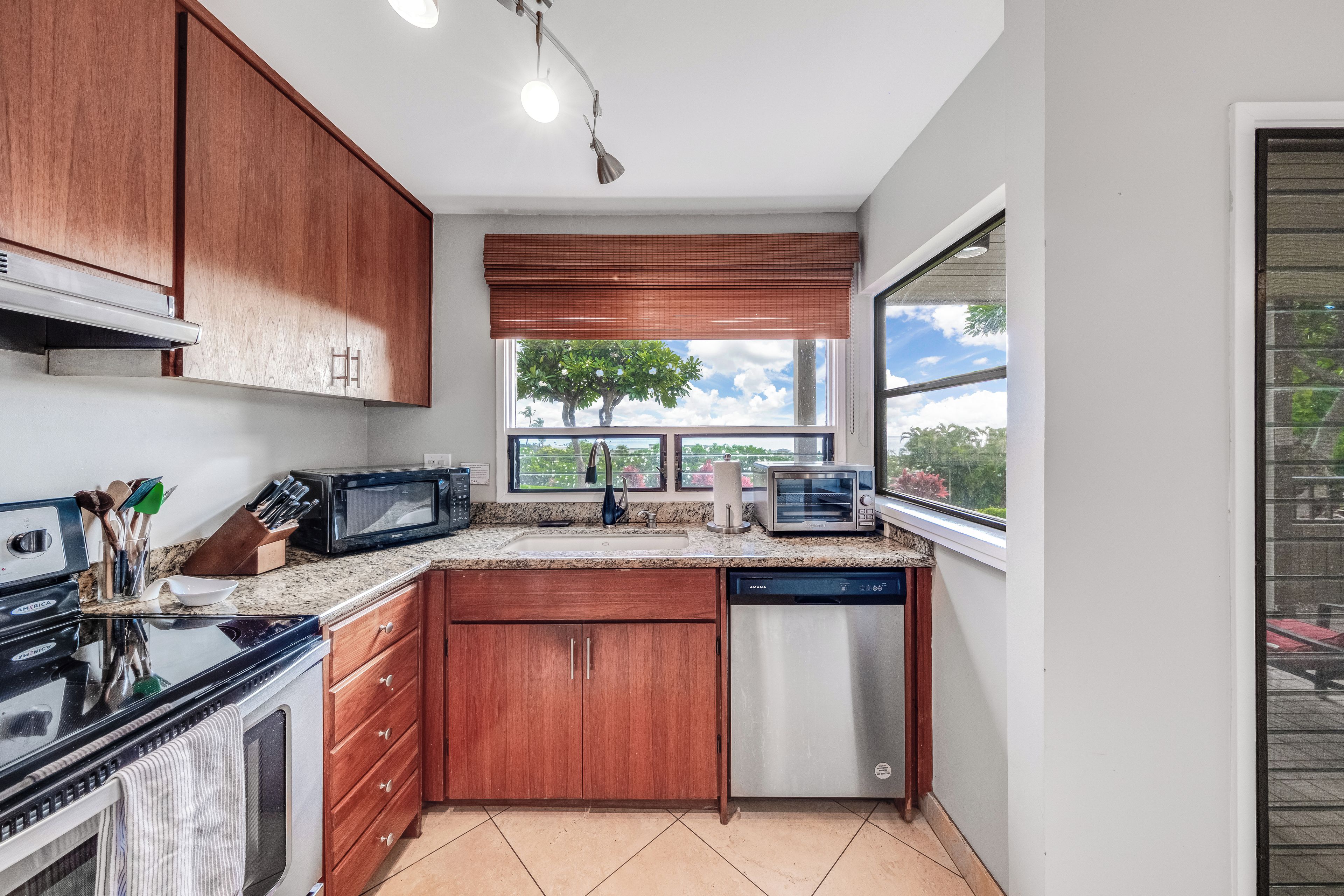 A kitchen with wooden cabinets, a microwave, a toaster, and a dishwasher.