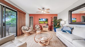 Un salon moderne avec un ventilateur de plafond, un canapé, une table basse et un fauteuil.