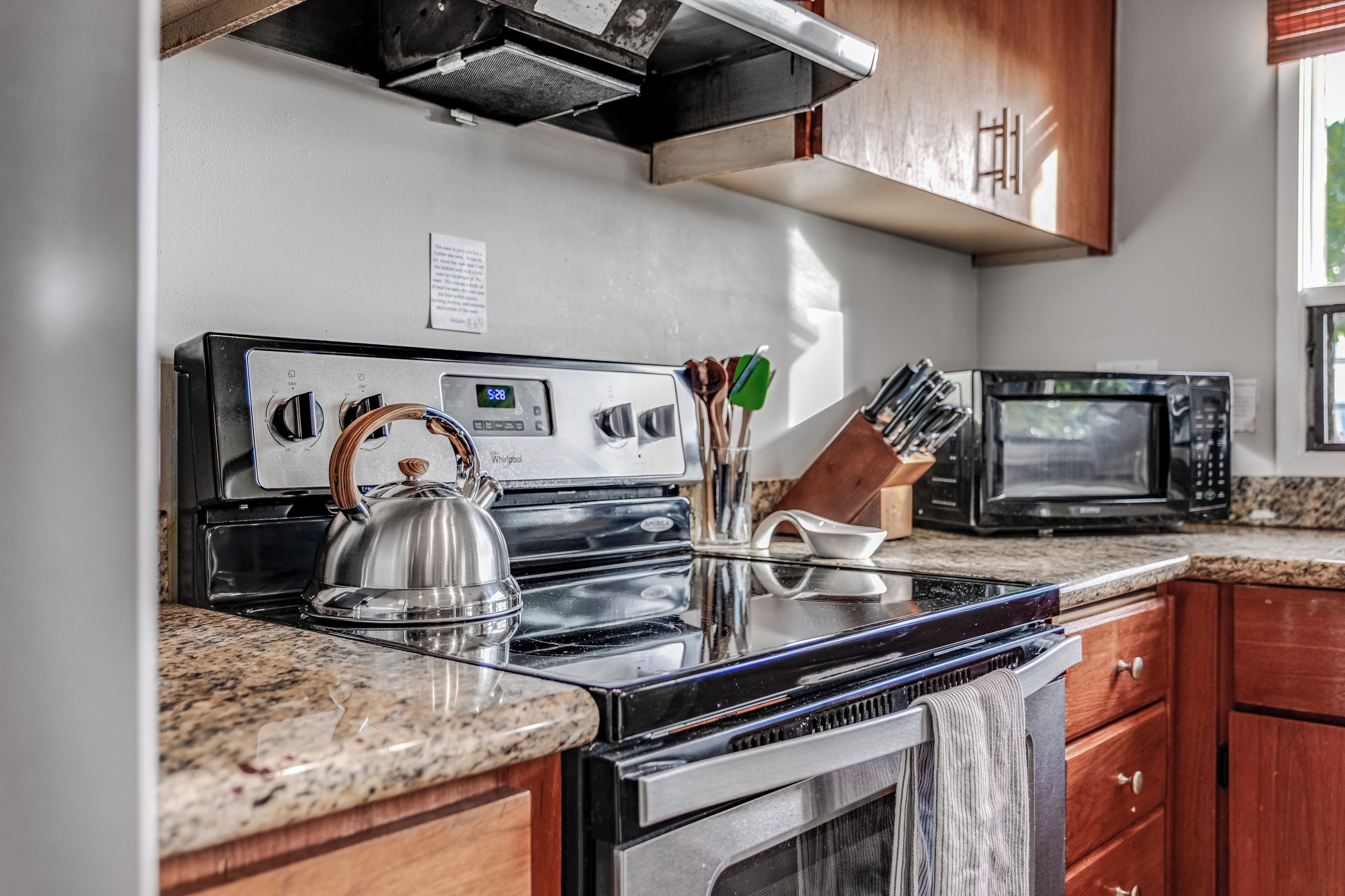 A kitchen with a stainless steel stove, a microwave, and wooden cabinets.