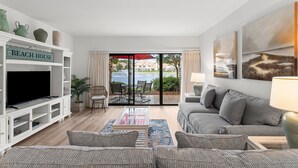 A living room with a TV, sofa, and a sign that reads "BEACH HOUSE". - Lake Views ~ Golf Cart ~ Community Pool (Miramar Beach)