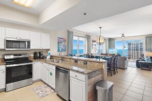 A modern kitchen with granite countertops, stainless steel appliances, and a view to the outside.