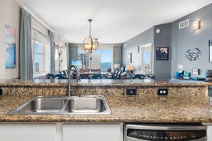 A modern kitchen with granite countertops, stainless steel appliances, and a view of the ocean.