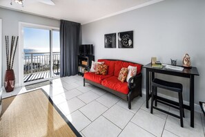 A modern living room with a red sofa, a black TV stand, and a balcony with a view.