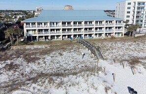 A multi-story hotel with balconies, a covered outdoor area, and a beach view.