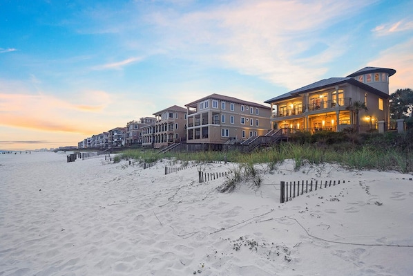 A beachfront property with multiple buildings, a sandy beach, and a wooden fence. - Bella Luna - Private Beachfront Retreat in Destiny by the Sea! (Destin)