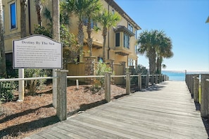 A wooden boardwalk leading to a building with a sign titled 'Destiny By The Sea'. - Bella Luna - Private Beachfront Retreat in Destiny by the Sea! (Destin)