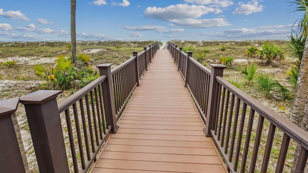 Un muelle de madera que conduce a una playa bajo un cielo despejado.