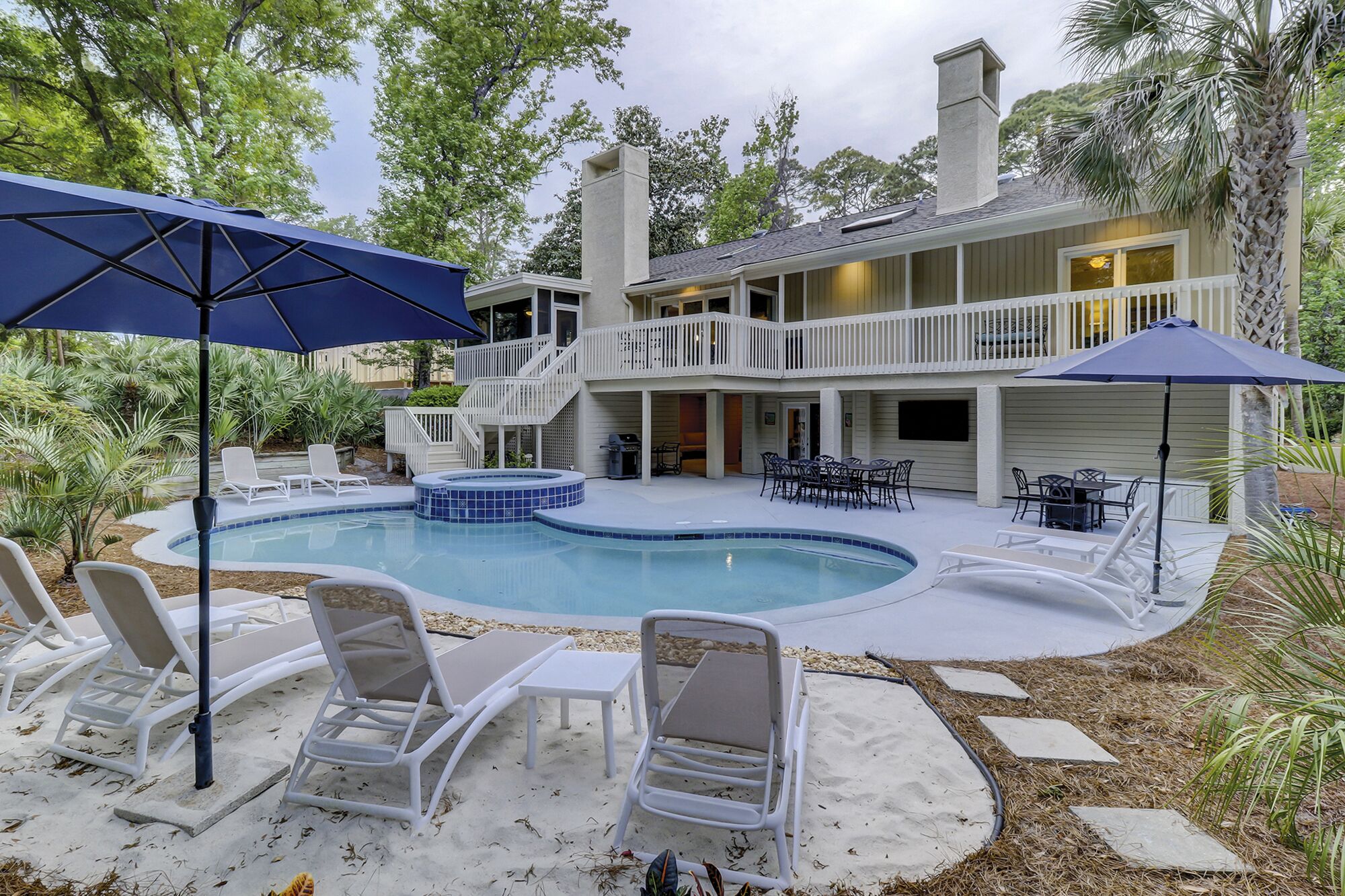 A two-story house with a swimming pool, outdoor furniture, and a covered patio area.
