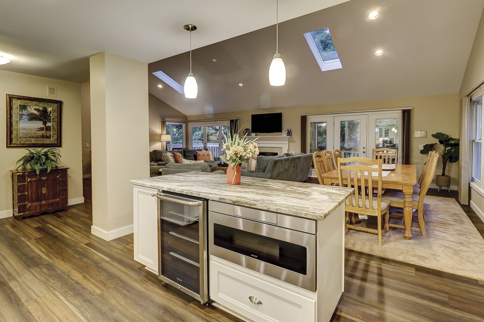 Una cocina amplia con una isla de mármol, electrodomésticos modernos y un comedor con mobiliario de madera.