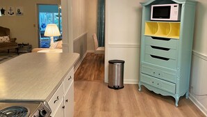 Une cuisine équipée d’une cuisinière en acier inoxydable, d’un four à micro-ondes de couleur turquoise et d’une poubelle.