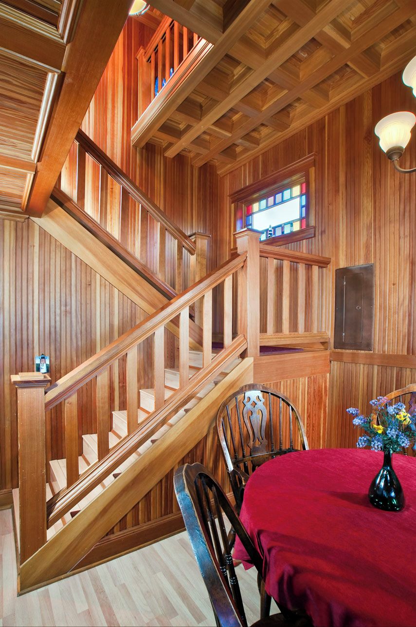 Una escalera de madera con una mesa y sillas rojas cerca.