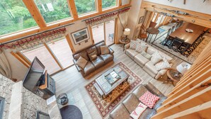 A spacious living area with a large window, a fireplace, and a cozy seating arrangement. - Dog Friendly Lakefront Retreat w/ Pool & Hot Tub (McHenry)