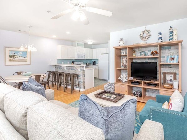A modern living room with a sofa, a coffee table, and a TV stand with decorative items. - South Beach Ocean 4 | Condo, Partial Ocean View! (Tybee Island)