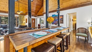 Un tavolo da pranzo in legno con soffitto alto e travi a vista, apparecchiato con piatti, posate e un vaso di fiori.