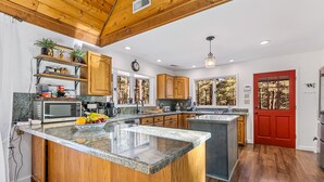 Una cucina moderna con mobili in legno, piani di lavoro in granito e una porta rossa.