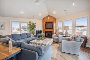 Ein geräumiges Wohnzimmer mit grauem Sofa, gestreiftem Hocker und Kamin.