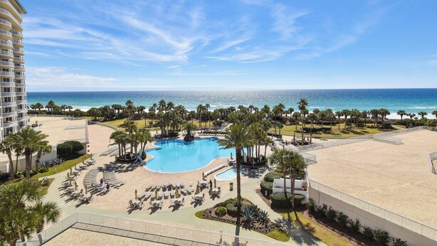 Un resort con una piscina grande, zona de playa y vista al océano.