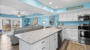 A modern kitchen with white cabinets, a granite countertop, and stainless steel appliances. - Unit 032 - Sandcastle 5B (Dauphin  Island)