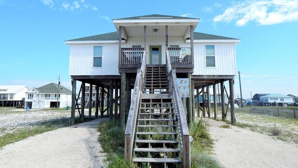 A two-story house with a wooden staircase leading to a balcony.