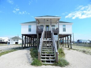 A two-story house with a wooden staircase leading to a balcony.