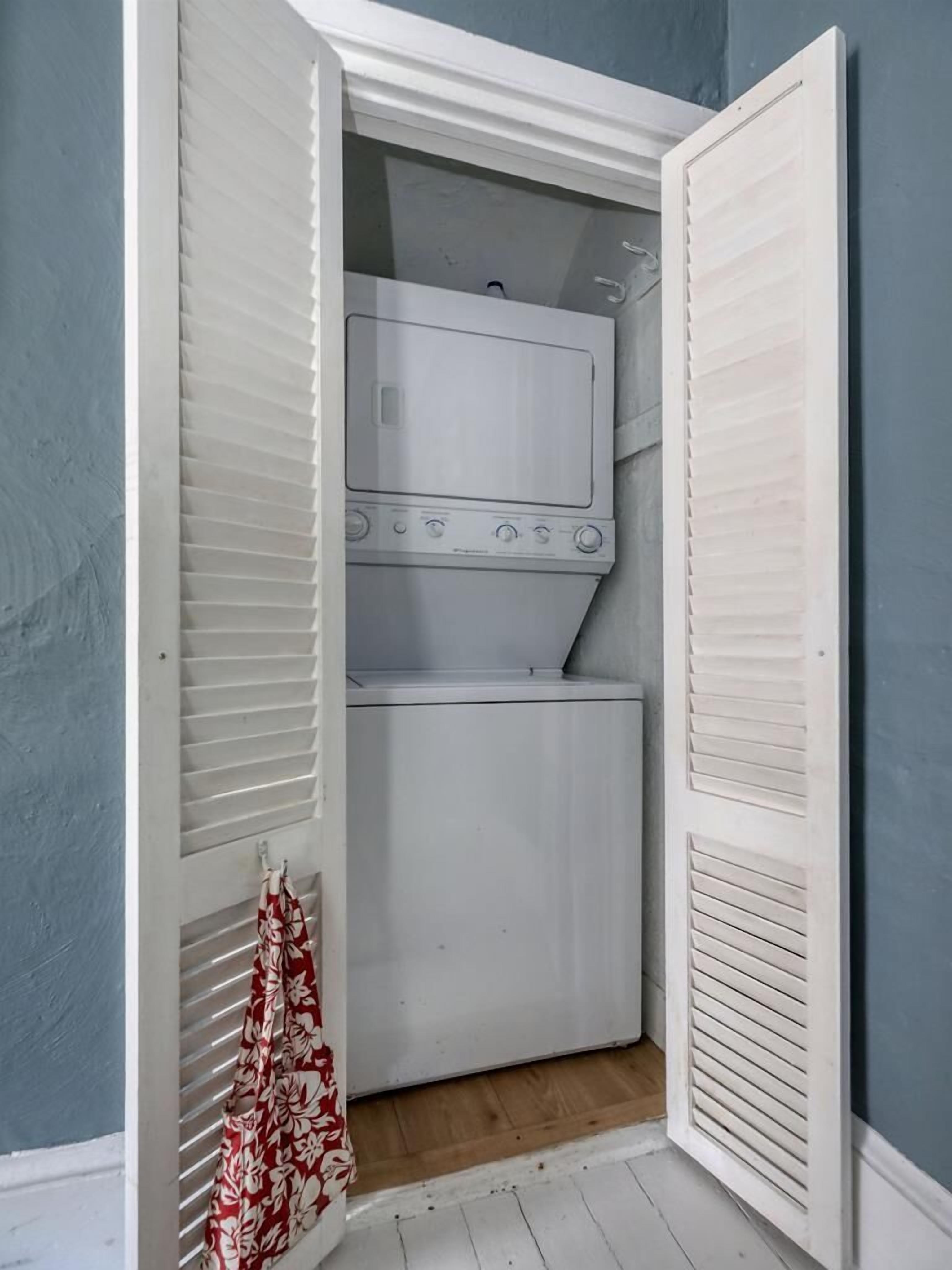 A laundry room with a washing machine and dryer, wooden flooring, and a towel hanging on the wall.