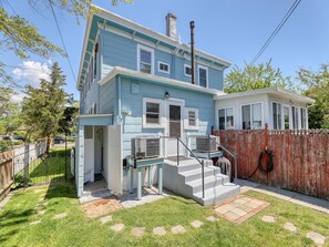 A two-story house with a blue exterior, a front porch, and a wooden fence.