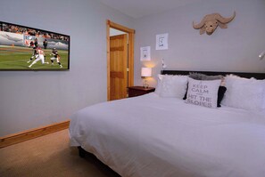 A bedroom with a bed, a TV on the wall, a lamp, and a wall-mounted decorative item. - The Grand Escape - Great Duplex on Elk. Hot tub (Crested Butte)