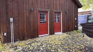 A wooden building with two red doors and a gravel driveway.
