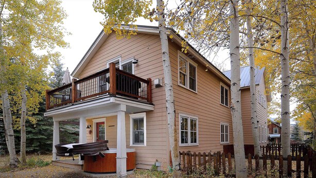 A two-story house with a balcony, a porch with a bench, and a wooden fence.