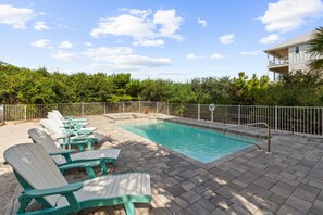 Une piscine avec des chaises longues et une terrasse délimitée par une clôture.