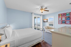 Une chambre à coucher comprenant un lit, une chaise, un bureau, un ventilateur de plafond et une fenêtre donnant sur un beau paysage.