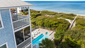 A two-story building with a balcony overlooking a swimming pool and a beach.