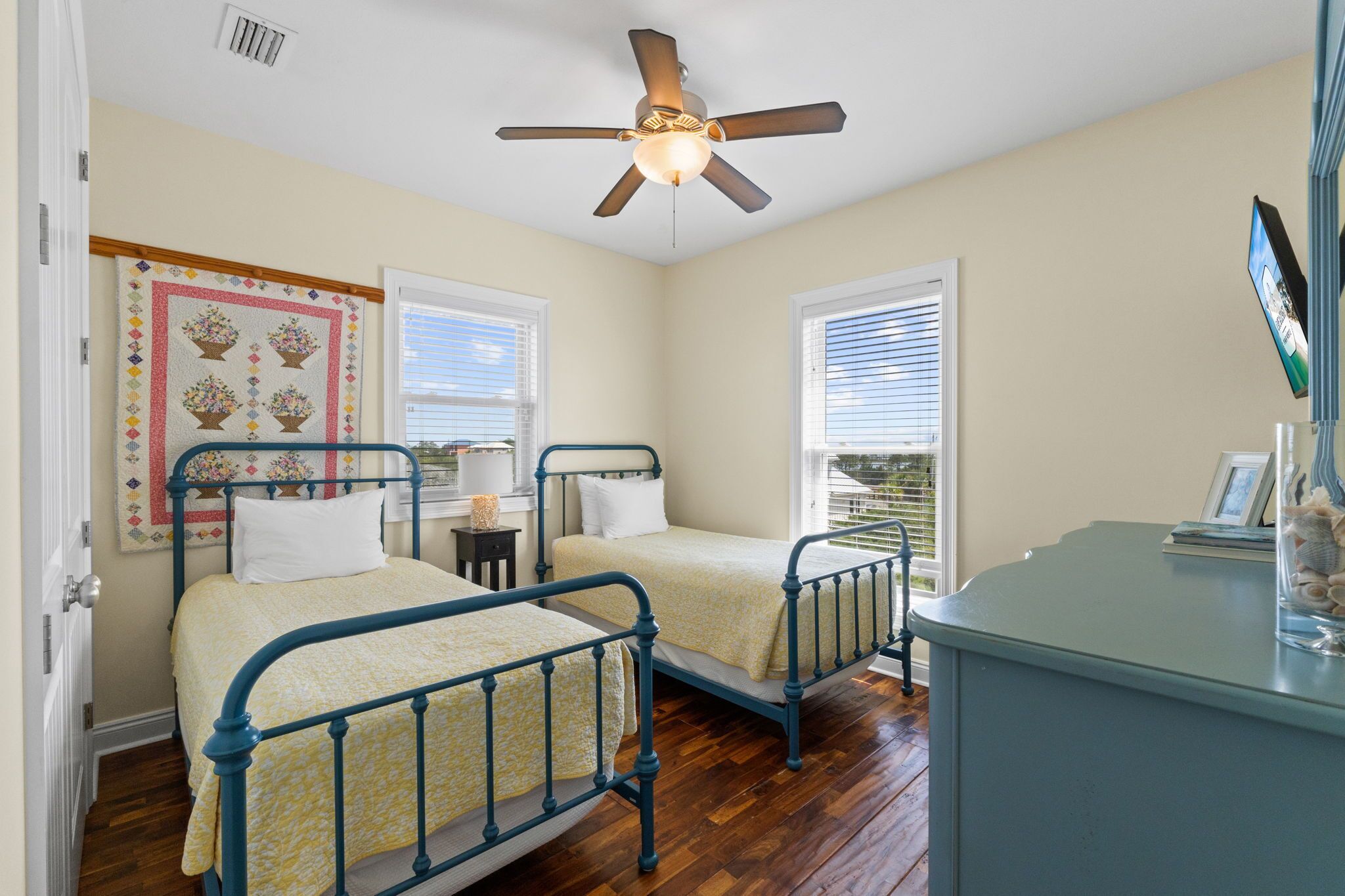 A bedroom with two beds, a ceiling fan, and a window with blinds.