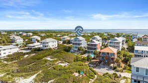 A coastal residential area with multiple two-story houses, some with balconies, and a clear view of the ocean.