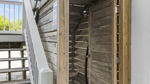 Un mur extérieur en bois, avec une porte en métal et une rambarde blanche.