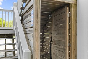 Un mur extérieur en bois, avec une porte en métal et une rambarde blanche.