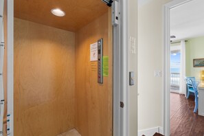 Un couloir intérieur en bois, avec une porte donnant sur une pièce offrant une vue sur l’océan.