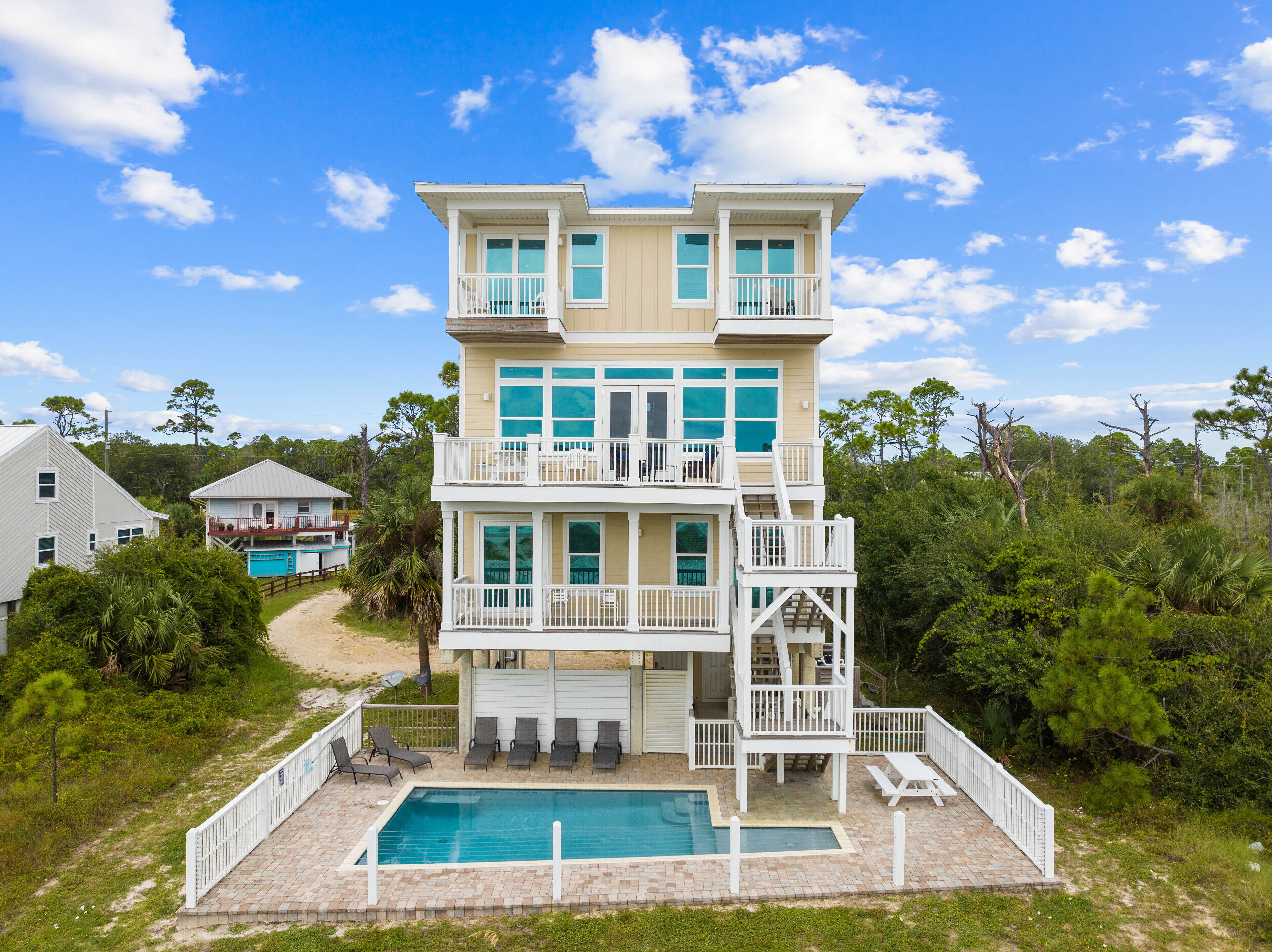 Une maison à plusieurs étages située en bord de mer, dotée d’une piscine, de balcons et offrant une vue sur l’océan.