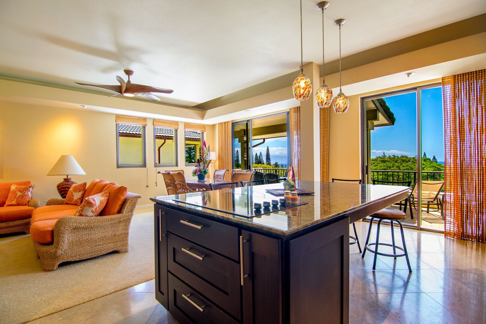 A modern kitchen with a central island, dining area with chairs, and a view of the outdoors.