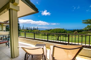 A balcony with a view of a golf course and ocean.